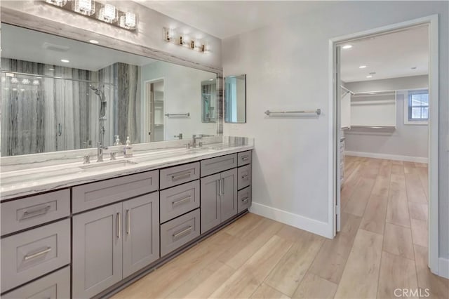 26242 Via Corrizo, San Juan Capistrano, CA 92675 - bathroom featuring double vanity, baseboards, a stall shower, wood finished floors, and a walk in closet