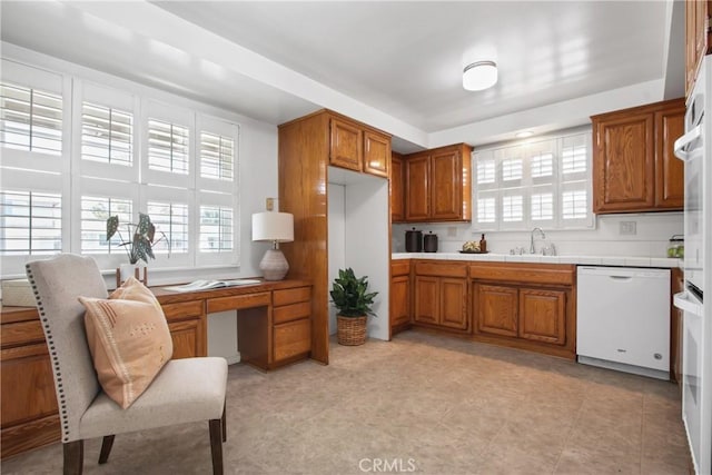 3441 Lilly Ave, Long Beach, CA 90808 - kitchen featuring white dishwasher, brown cabinets, a sink, tile counters, and plenty of natural light