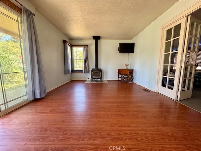 10265 Nancy Ave, Cherry Valley, CA 92223 - unfurnished living room with wood finished floors, a wood stove, a textured ceiling, and baseboards