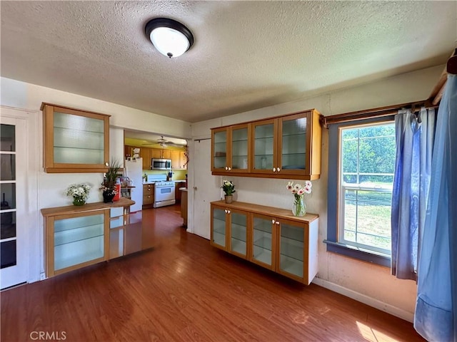 10265 Nancy Ave, Cherry Valley, CA 92223 - kitchen featuring white appliances, a textured ceiling, dark wood-style flooring, healthy amount of natural light, and brown cabinets