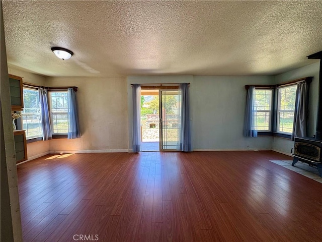 10265 Nancy Ave, Cherry Valley, CA 92223 - unfurnished living room with a wood stove, wood finished floors, a textured ceiling, plenty of natural light, and baseboards