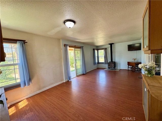 10265 Nancy Ave, Cherry Valley, CA 92223 - unfurnished living room with a textured ceiling, wood finished floors, a wood stove, and baseboards