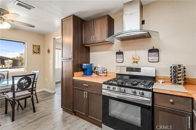 24438 Sage Ave, Boron, CA 93516 - kitchen with stainless steel gas range, island range hood, light countertops, light wood-style floors, and a ceiling fan