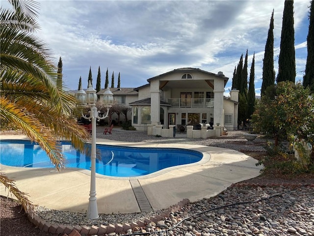 7614 Calpella Ave, Hesperia, CA 92345 - rear view of house with a balcony, a patio area, an outdoor pool, and stucco siding
