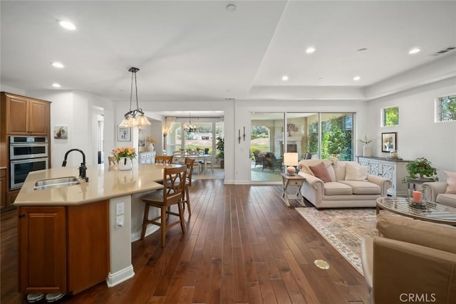 1494 Vista Tesoro Pl, Nipomo, CA 93444 - kitchen featuring a sink, open floor plan, brown cabinetry, light countertops, and dark wood finished floors