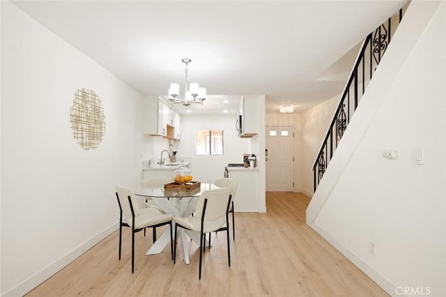 14803 Vanowen St Unit 9, Van Nuys, CA 91405 - dining area featuring a chandelier, light wood finished floors, stairs, and baseboards