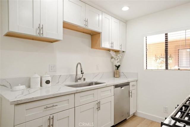 14803 Vanowen St Unit 9, Van Nuys, CA 91405 - kitchen featuring stainless steel dishwasher, a sink, light wood finished floors, white cabinets, and light stone countertops