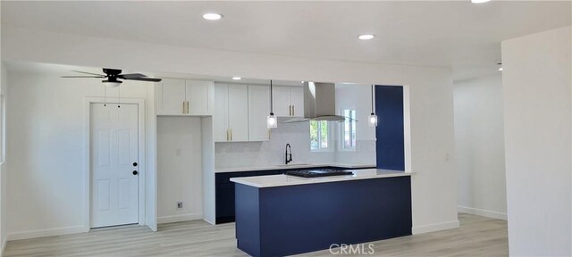 3355 Debbie Ln, Riverside, CA 92501 - kitchen featuring wall chimney range hood, a ceiling fan, light countertops, backsplash, and light wood-type flooring