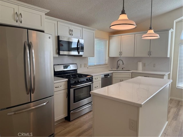 140 W Pioneer Ave Unit 134, Redlands, CA 92374 - kitchen with stainless steel appliances, light wood finished floors, a sink, pendant lighting, and a textured ceiling