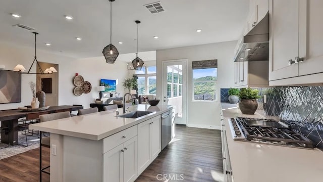 27225 Cranmore Way Unit 302, Valencia, CA 91381 - kitchen featuring appliances with stainless steel finishes, dark wood finished floors, under cabinet range hood, a sink, and a kitchen breakfast bar