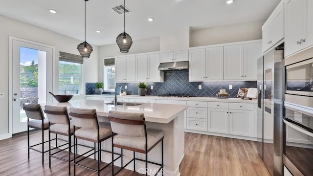 27225 Cranmore Way Unit 302, Valencia, CA 91381 - kitchen with a sink, stainless steel appliances, backsplash, light countertops, and light wood-style flooring