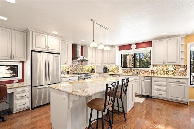 720 E Mountain Ridge Rd, Lake Almanor, CA 96137 - kitchen featuring stainless steel appliances, wall chimney range hood, a kitchen island, wood finished floors, and light stone counters