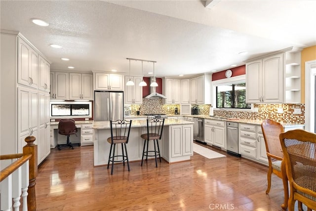 720 E Mountain Ridge Rd, Lake Almanor, CA 96137 - kitchen with appliances with stainless steel finishes, wall chimney range hood, a kitchen breakfast bar, tasteful backsplash, and recessed lighting