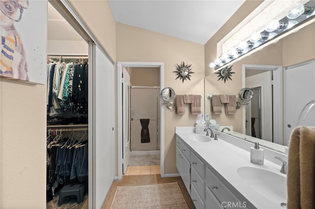 23981 Via Astuto, Murrieta, CA 92562 - bathroom featuring double vanity, a walk in closet, tile patterned floors, vaulted ceiling, and a shower with door