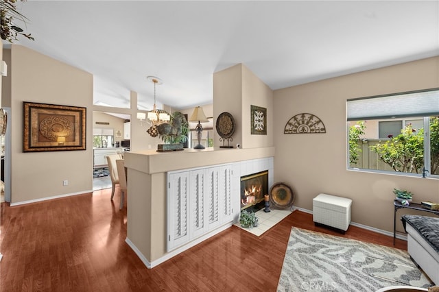 23981 Via Astuto, Murrieta, CA 92562 - living area with vaulted ceiling, a chandelier, wood finished floors, a tiled fireplace, and baseboards