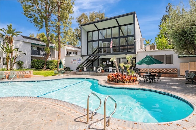 18645 Hatteras St Unit 203, Tarzana, CA 91356 - back of house with stairway, a community pool, a patio area, and stucco siding