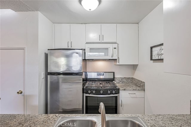 18645 Hatteras St Unit 203, Tarzana, CA 91356 - kitchen with appliances with stainless steel finishes, white cabinetry, light stone counters, and a sink
