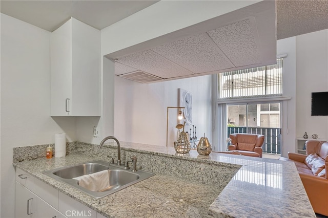 18645 Hatteras St Unit 203, Tarzana, CA 91356 - kitchen featuring a sink, white cabinets, light stone countertops, a drop ceiling, and open floor plan