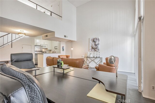 18645 Hatteras St Unit 203, Tarzana, CA 91356 - dining space featuring a towering ceiling, stairway, dark wood-style floors, and baseboards