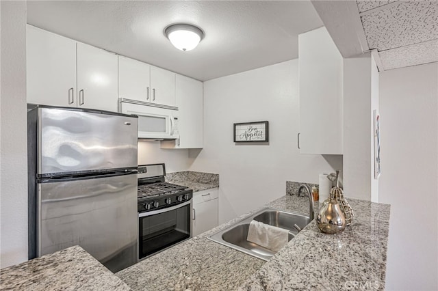18645 Hatteras St Unit 203, Tarzana, CA 91356 - kitchen with stainless steel appliances, a sink, white cabinets, and light stone counters