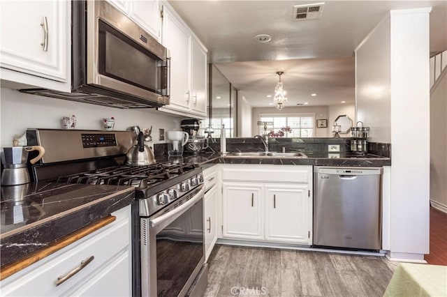 5538 Las Virgenes Rd Unit 142, Calabasas, CA 91302 - kitchen with appliances with stainless steel finishes, a sink, dark countertops, white cabinetry, and light wood-type flooring