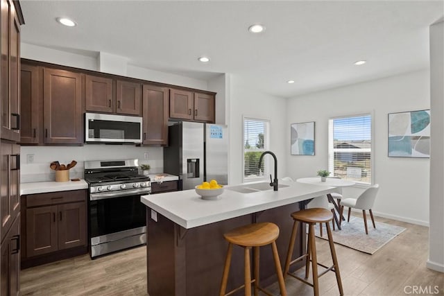 5560 Keith Rd, Paradise, CA 95969 - kitchen featuring stainless steel appliances, light countertops, light wood-style flooring, a breakfast bar area, and a center island with sink