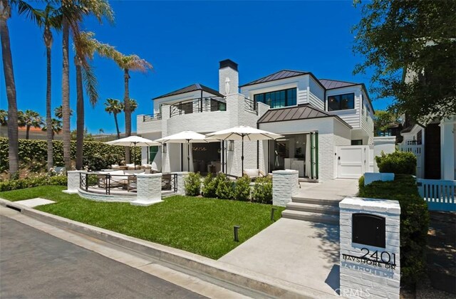 2401 Bayshore Dr, Newport Beach, CA 92663 - view of front facade featuring a standing seam roof, metal roof, a gate, a chimney, and brick siding