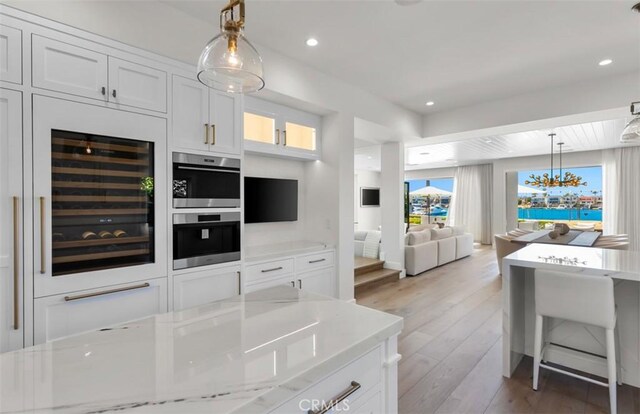 2401 Bayshore Dr, Newport Beach, CA 92663 - kitchen with beverage cooler, light wood finished floors, pendant lighting, white cabinetry, and recessed lighting