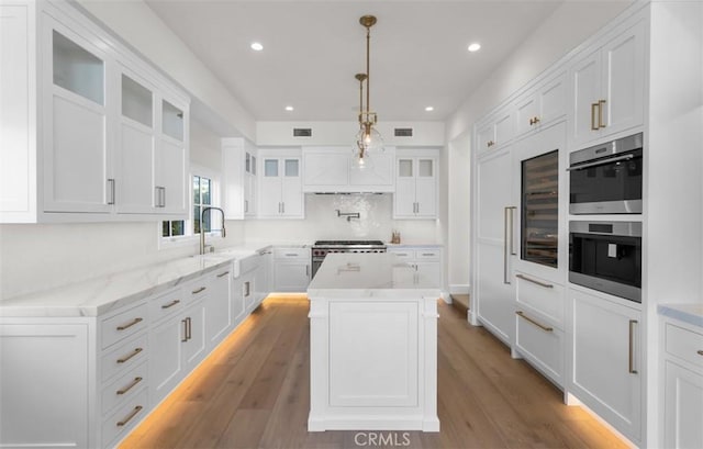 2401 Bayshore Dr, Newport Beach, CA 92663 - kitchen featuring appliances with stainless steel finishes, white cabinetry, light wood-type flooring, wine cooler, and glass insert cabinets