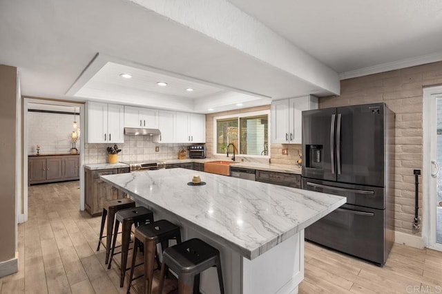 9739 Carta Ln, El Cajon, CA 92021 - kitchen with stainless steel appliances, a tray ceiling, light wood-type flooring, a sink, and white cabinetry