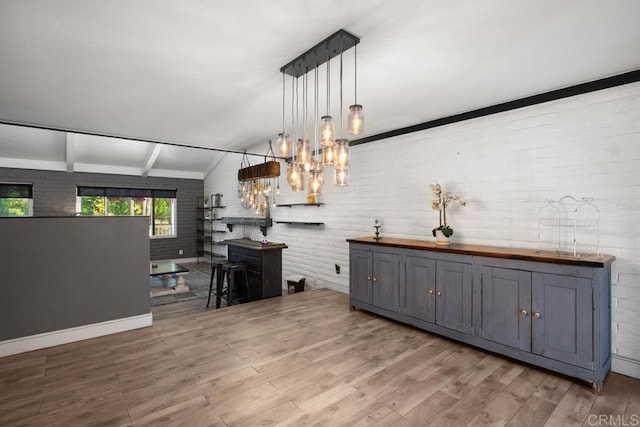 9739 Carta Ln, El Cajon, CA 92021 - kitchen with butcher block countertops, wood finished floors, a chandelier, gray cabinets, and brick wall