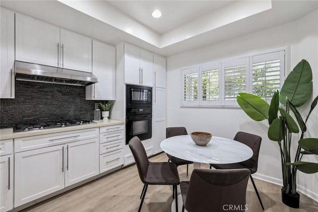 450 San Vicente Blvd Unit 203, Santa Monica, CA 90402 - kitchen with black appliances, under cabinet range hood, tasteful backsplash, white cabinets, and light countertops