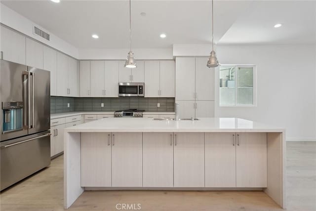 1746 Garfield Pl Unit 101, Los Angeles, CA 90028 - kitchen featuring stainless steel appliances, decorative backsplash, a spacious island, light countertops, and a sink