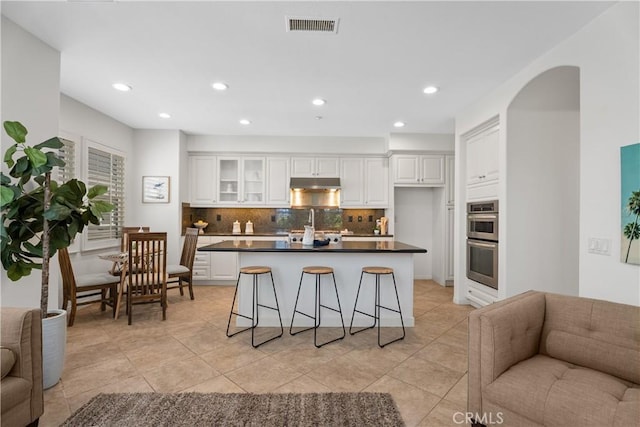 6249 Pacific Pointe Dr Unit 16, Huntington Beach, CA 92648 - kitchen with open floor plan, double oven, dark countertops, backsplash, and white cabinets