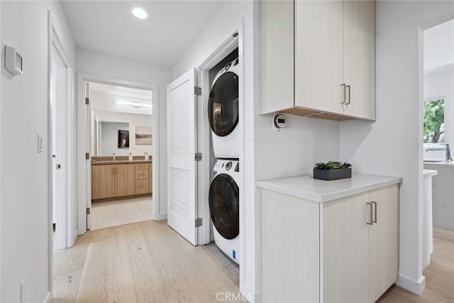 1746 Garfield Pl Unit 203, Los Angeles, CA 90028 - laundry area with stacked washing machine and dryer, light wood-style floors, recessed lighting, baseboards, and cabinet space