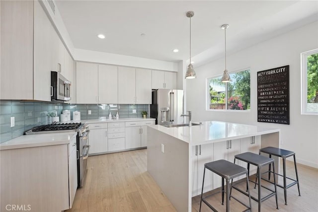 1746 Garfield Pl Unit 203, Los Angeles, CA 90028 - kitchen with appliances with stainless steel finishes, light wood-style flooring, a sink, a kitchen breakfast bar, and backsplash