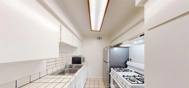 4660 Coldwater Canyon Ave Unit 4, Studio City, CA 91604 - kitchen with white gas stove, under cabinet range hood, tile countertops, stainless steel microwave, and white cabinets