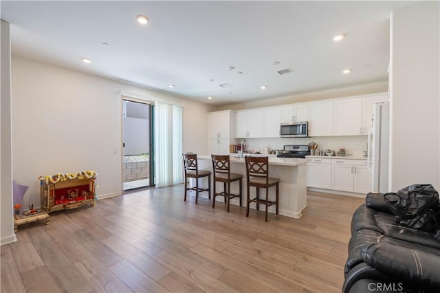 956 W Clover Ave, Rialto, CA 92376 - kitchen with stainless steel appliances, open floor plan, white cabinets, a center island with sink, and a breakfast bar area
