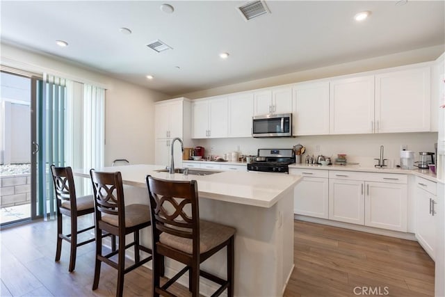956 W Clover Ave, Rialto, CA 92376 - kitchen featuring stainless steel appliances, light wood-type flooring, a kitchen island with sink, a breakfast bar, and recessed lighting