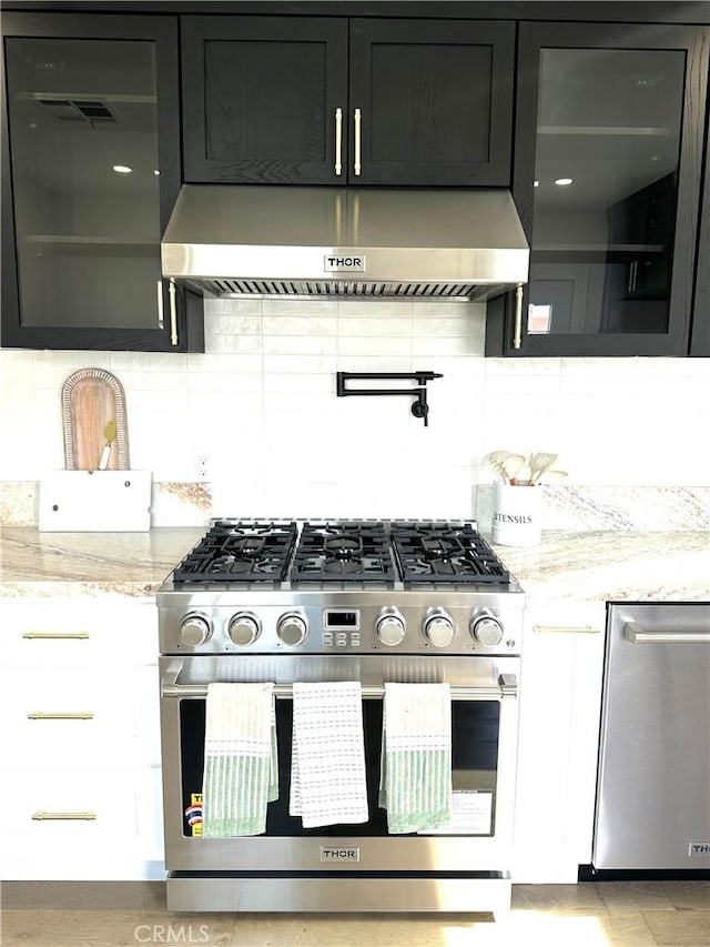 16913 Covello St, Van Nuys, CA 91406 - kitchen featuring appliances with stainless steel finishes, wall chimney range hood, backsplash, and light stone countertops