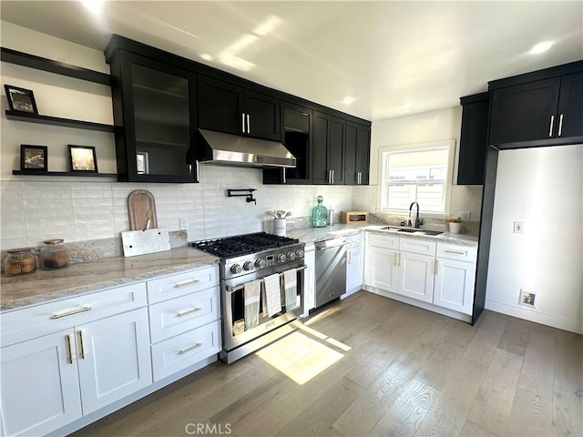 16913 Covello St, Van Nuys, CA 91406 - kitchen featuring stainless steel appliances, under cabinet range hood, light wood-style flooring, light stone counters, and dark cabinetry