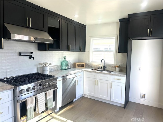 16913 Covello St, Van Nuys, CA 91406 - kitchen featuring under cabinet range hood, stainless steel appliances, dark cabinetry, light wood-style flooring, and light stone countertops