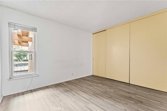105 Tangelo Unit 400, Irvine, CA 92618 - unfurnished bedroom with light wood-style flooring, a closet, and a textured ceiling