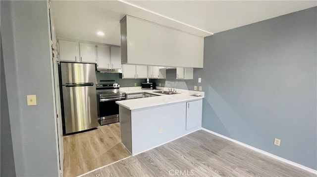 6815 Remmet Ave Unit 219, Canoga Park, CA 91303 - kitchen with stainless steel appliances, a peninsula, light wood finished floors, light countertops, and under cabinet range hood