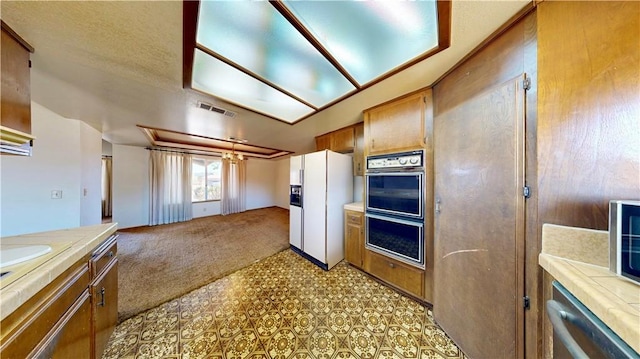 20061 Seneca Rd, Apple Valley, CA 92307 - kitchen featuring white fridge with ice dispenser, multiple ovens, light carpet, light countertops, and brown cabinetry