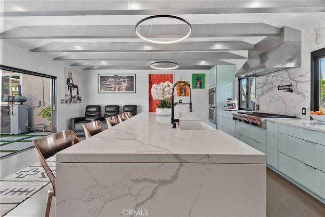 16302 Graystone Ave, Norwalk, CA 90650 - kitchen with gas stovetop, a sink, a center island with sink, beam ceiling, and double oven