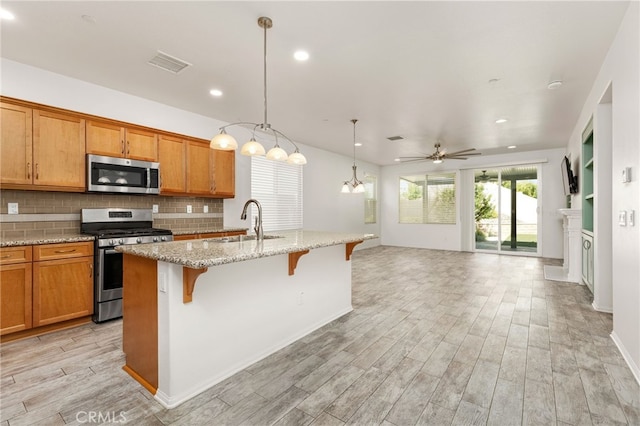 1536 Williamson, Beaumont, CA 92223 - kitchen with stainless steel appliances, a sink, open floor plan, a kitchen breakfast bar, and light wood finished floors