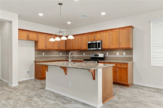 1536 Williamson, Beaumont, CA 92223 - kitchen with stainless steel appliances, brown cabinets, light stone countertops, a sink, and light wood-type flooring