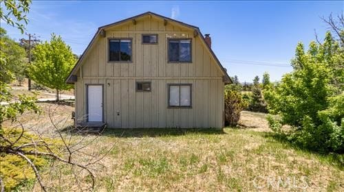 28921 Bear Valley Rd, Tehachapi, CA 93561 - back of property with a chimney, board and batten siding, a gambrel roof, and a yard