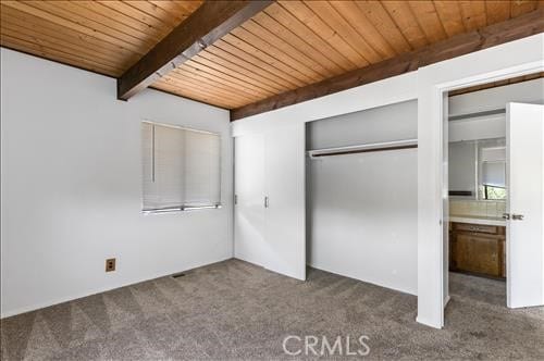 28921 Bear Valley Rd, Tehachapi, CA 93561 - unfurnished bedroom featuring wood ceiling with exposed beams, carpet, and a closet